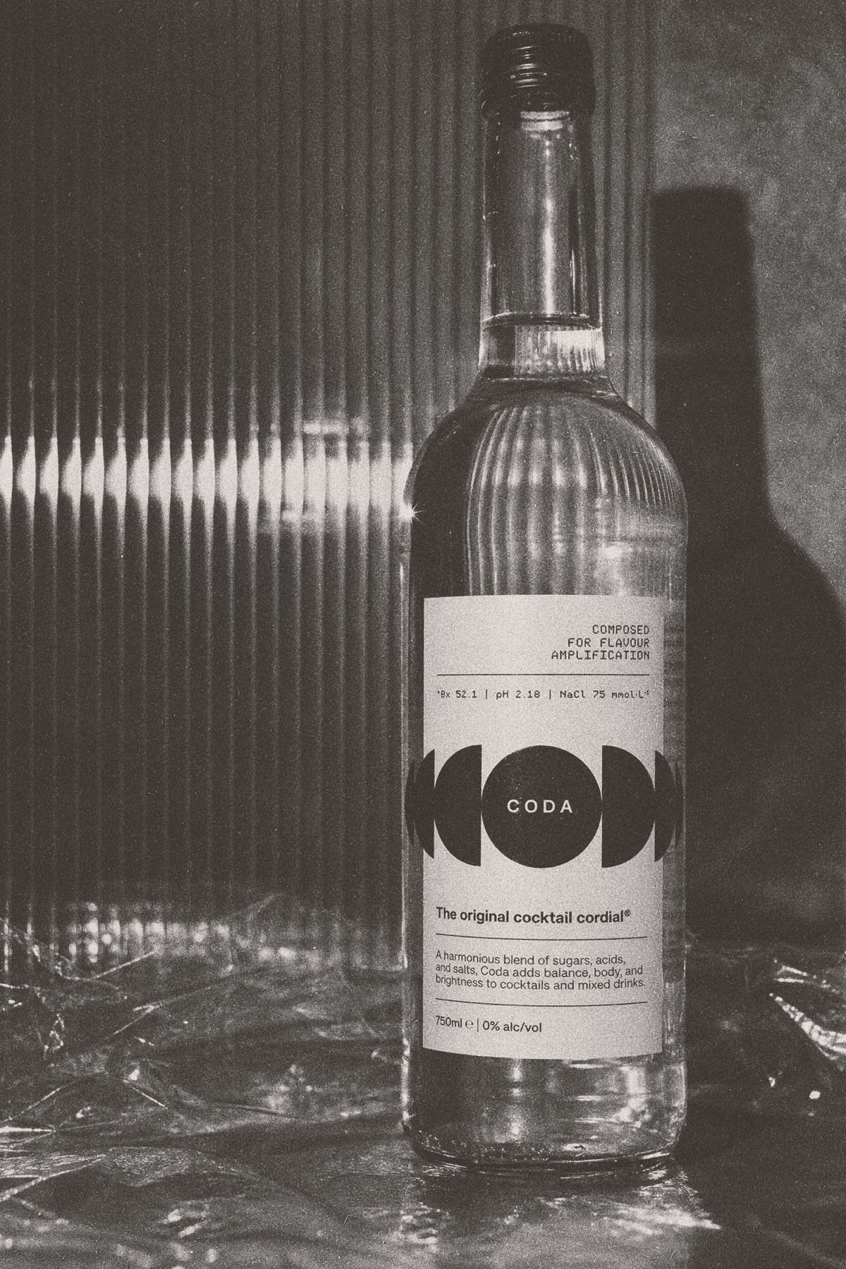 The Coda bottle beside a glass, hard light