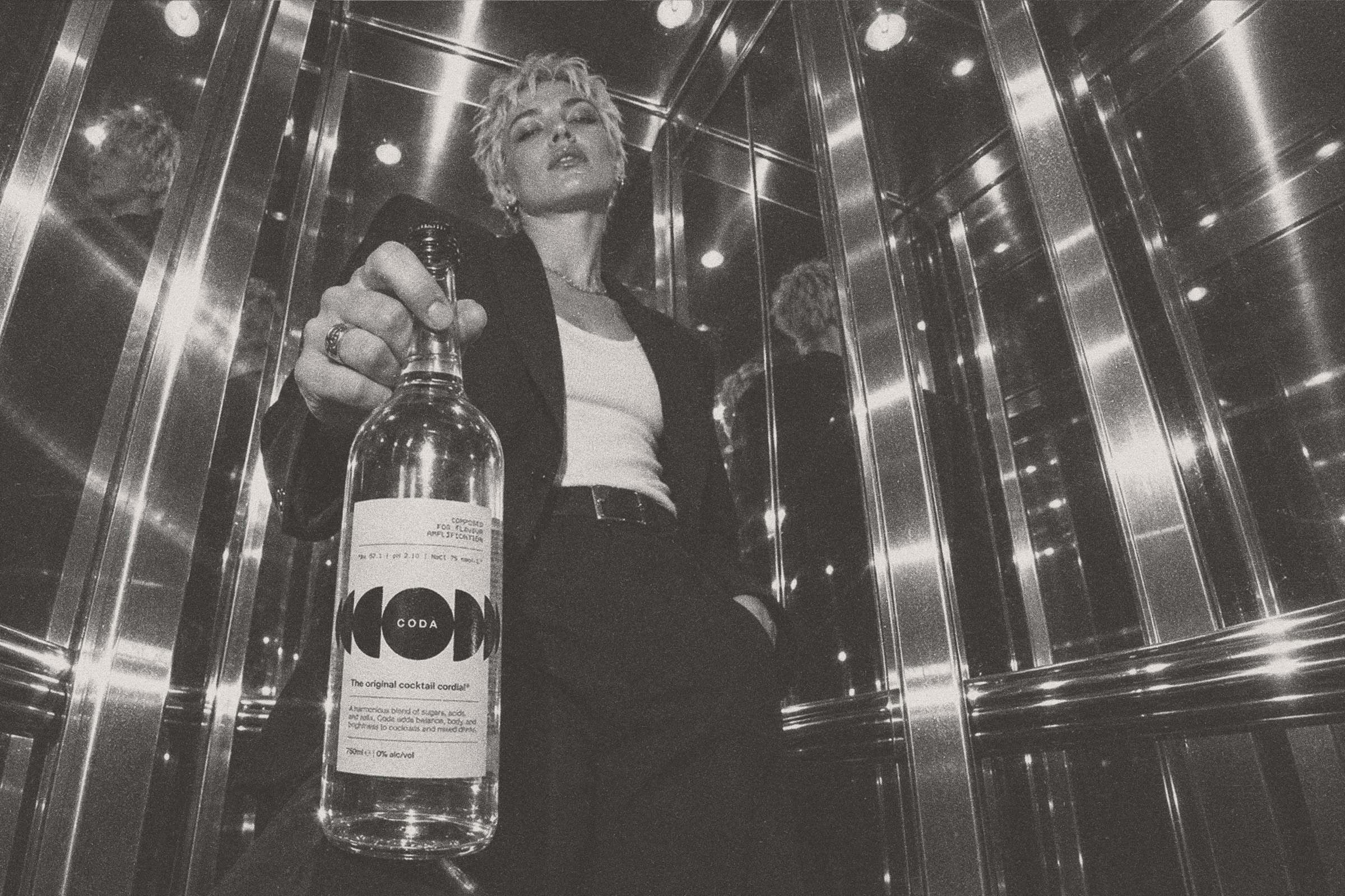In a mirrored room, holding the bottle